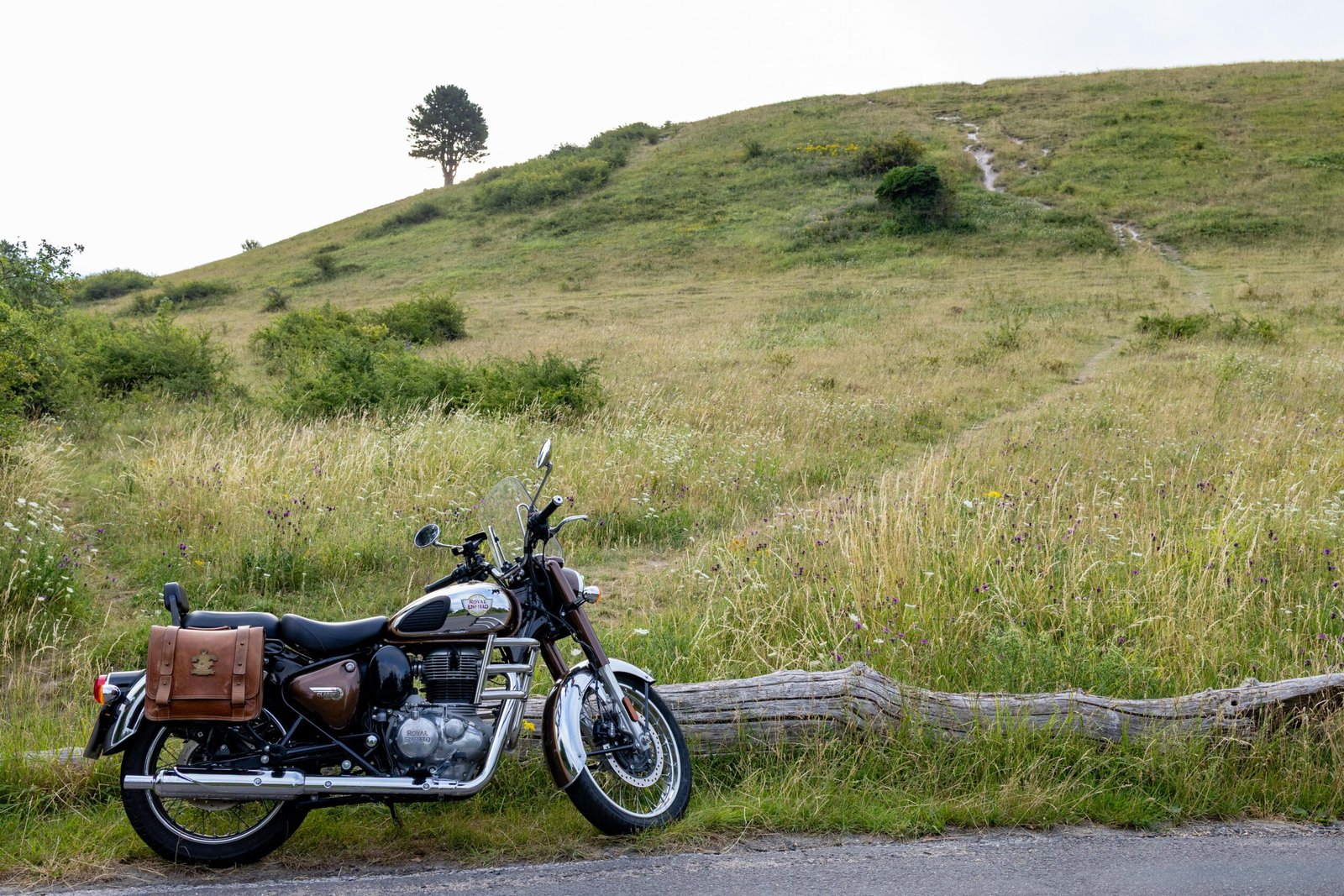Motorcycle parked on the grassy trail below Ivinghoe Beacon with a single tree on the hillside