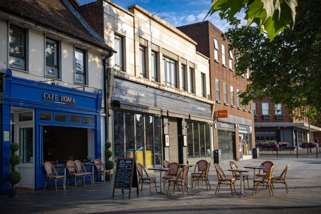 Café Roma and neighbouring shopfronts on a St Albans street, with outdoor tables