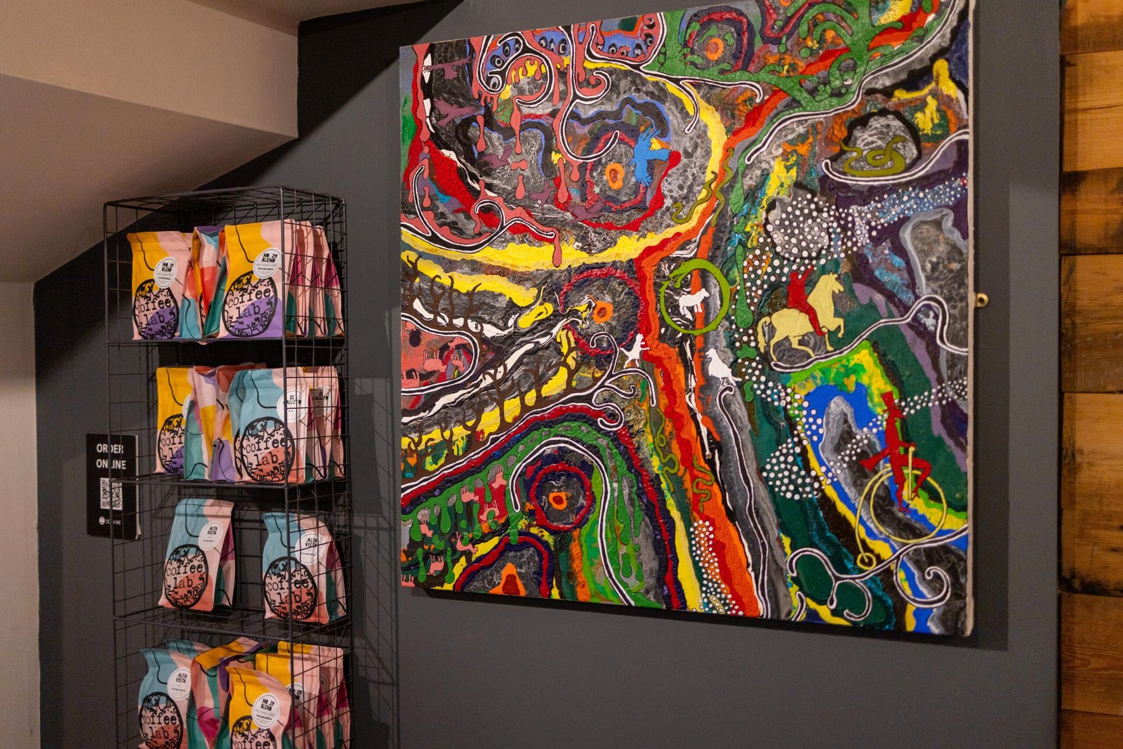Colourful abstract artwork above a retail rack of Coffee Lab coffee bags