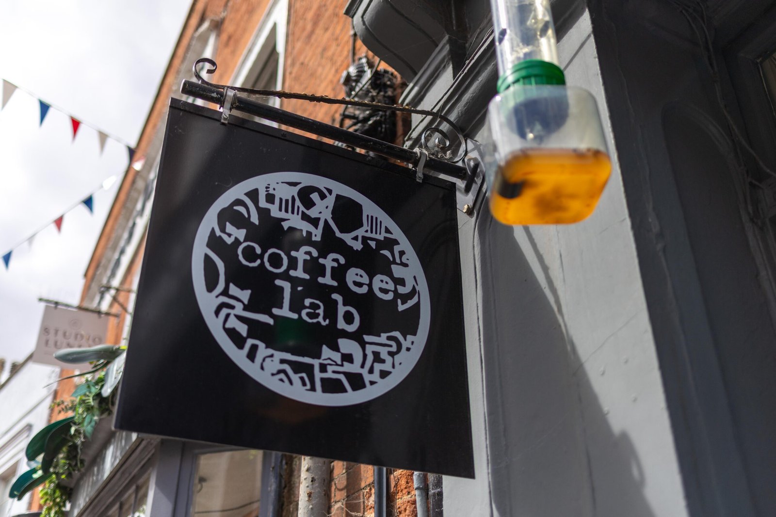 Coffee Lab hanging shop sign above the Hitchin storefront, with bunting in the background