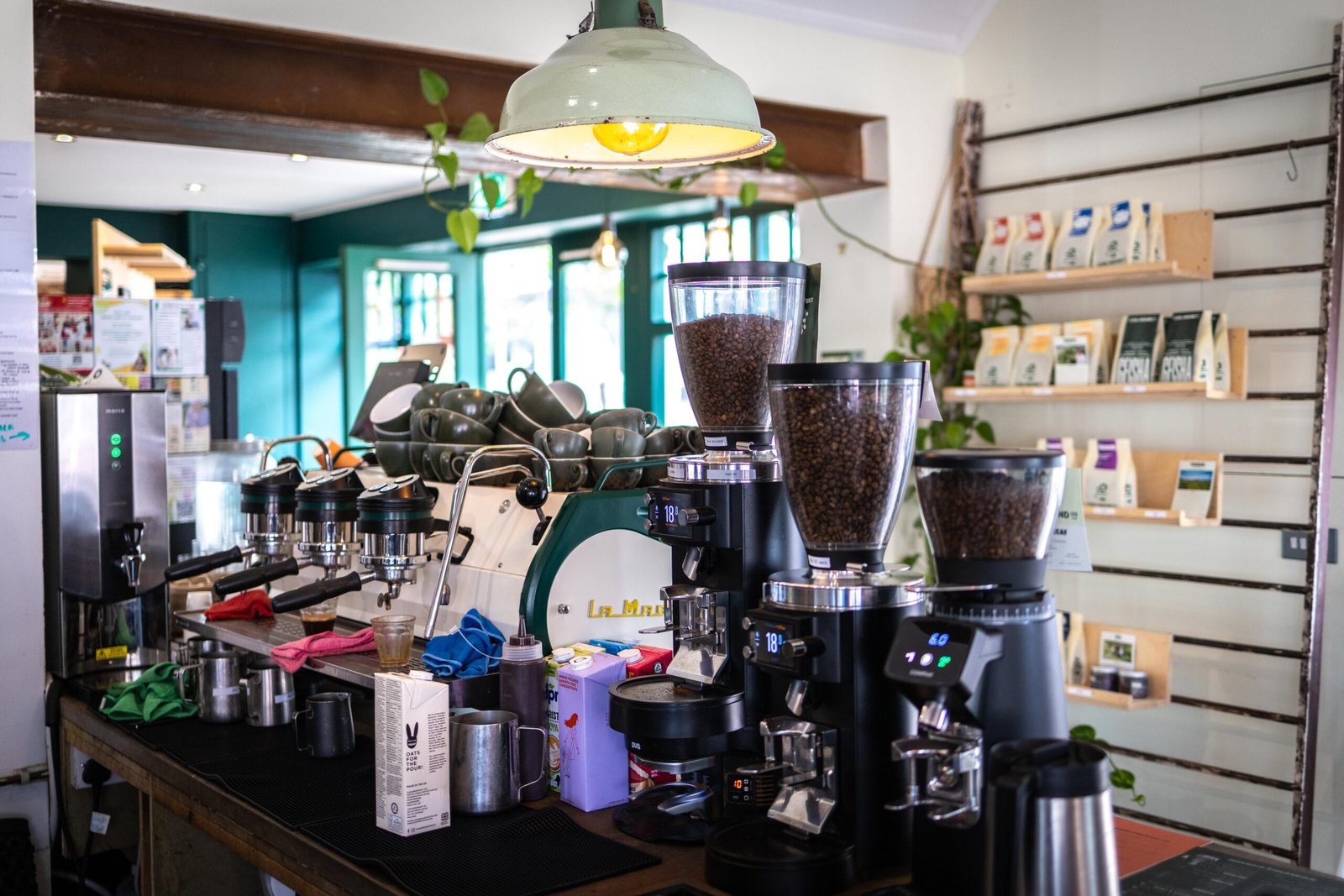 Espresso machine, grinders, and retail coffee bags on the shelf at Level Ground Co