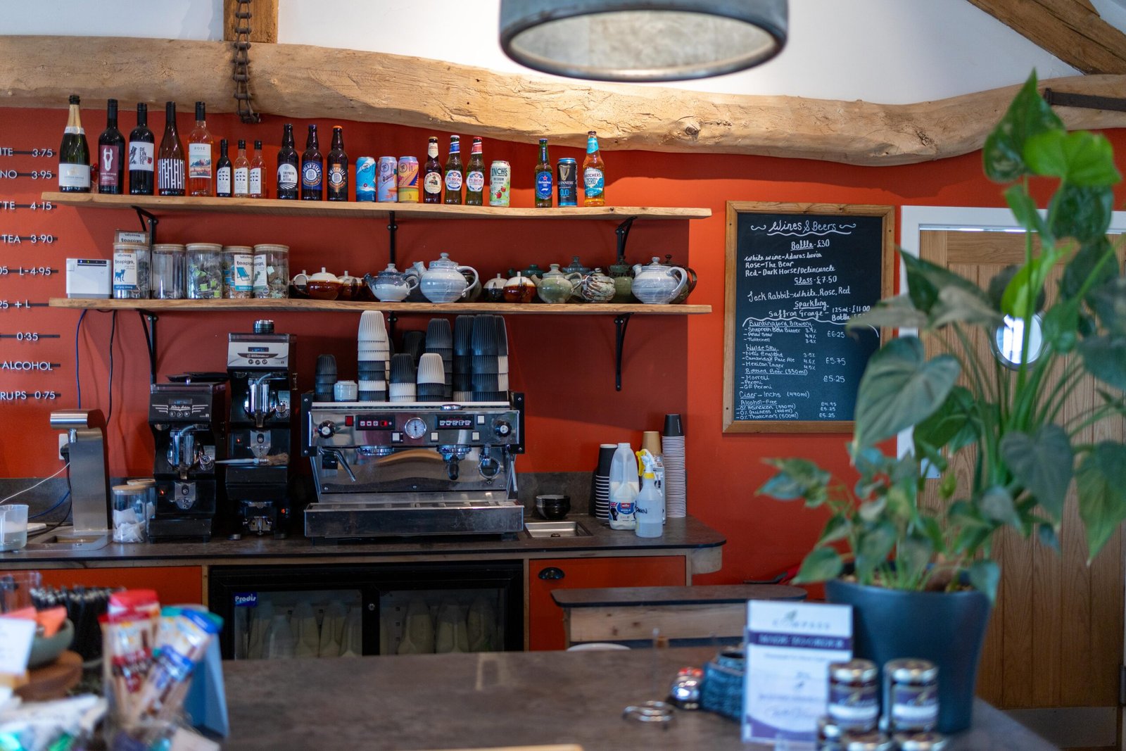 Espresso counter at The Mixing Shed Cafe with terracotta walls, exposed beams, and a wines and beers chalkboard
