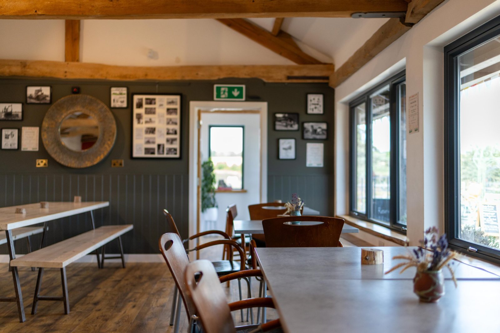 Interior seating at The Mixing Shed Cafe with vaulted beam ceiling, dark green wainscoting, and framed historical farm photos
