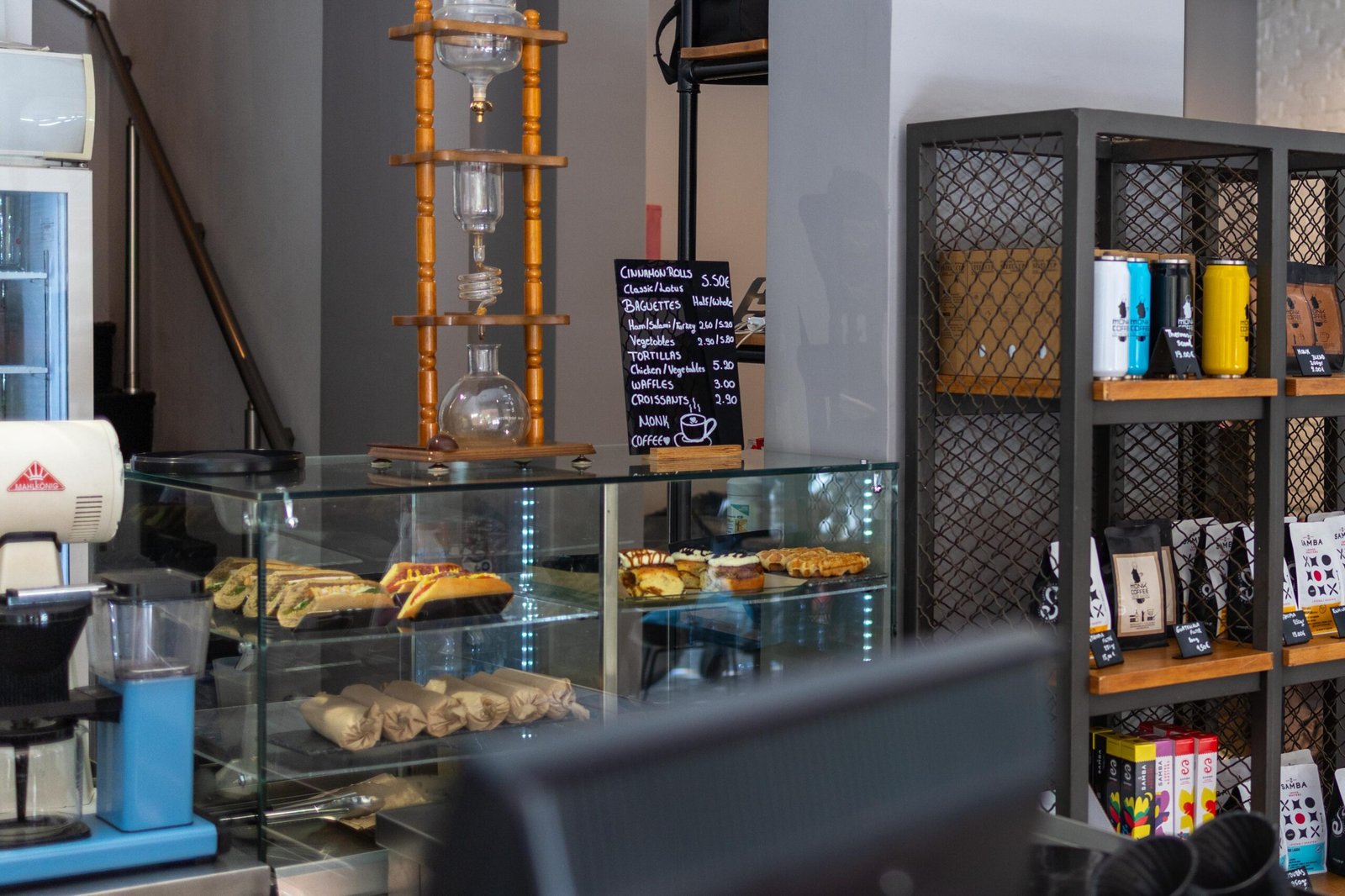 A Kyoto-style cold drip tower on a wooden stand next to the chalkboard menu at Monk Coffee