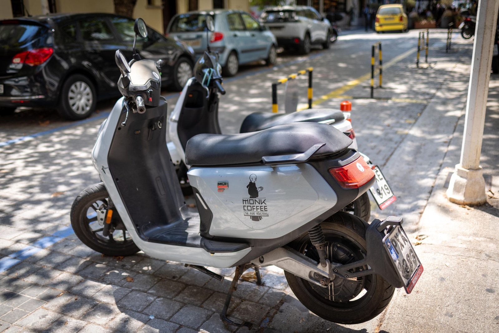 A Monk Coffee branded delivery scooter parked on a street in Rhodes Town