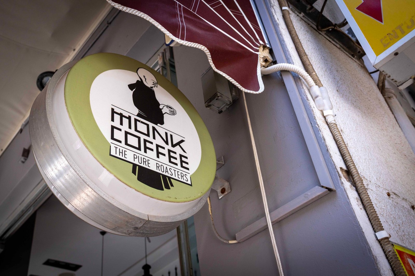 The round hanging Monk Coffee/The Pure Roasters sign outside the shop