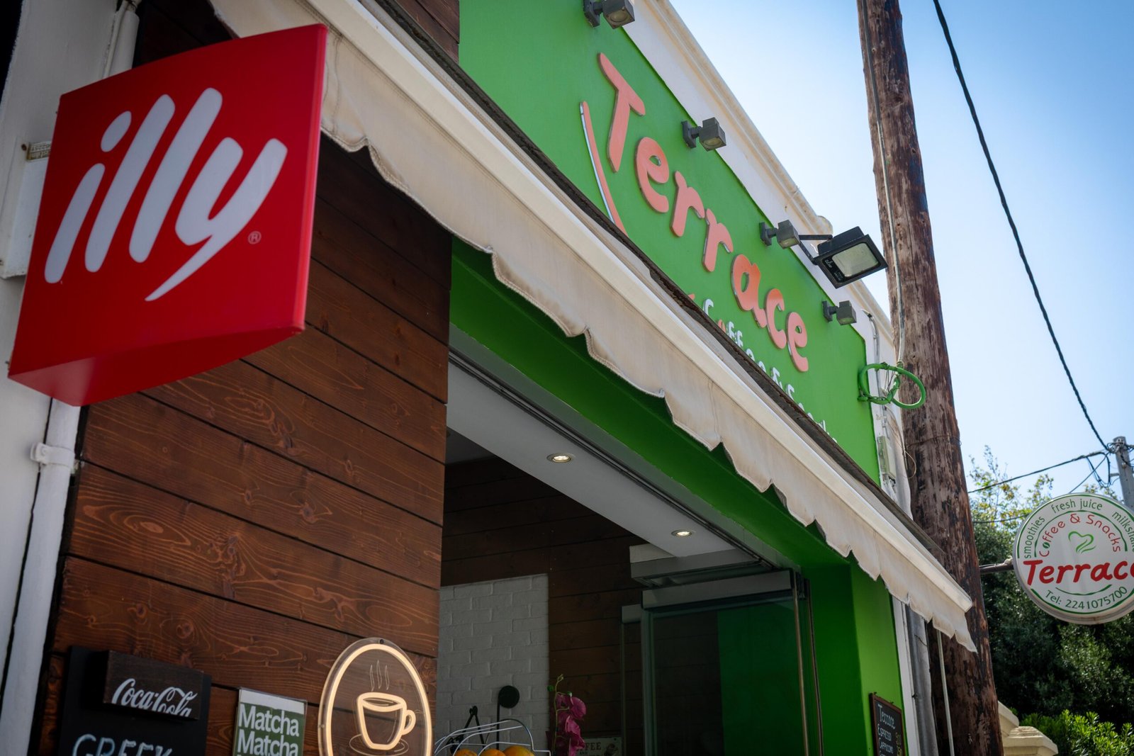 The exterior of Terrace Coffee & Snacks in Rhodes Town, with an illy sign and the green shopfront