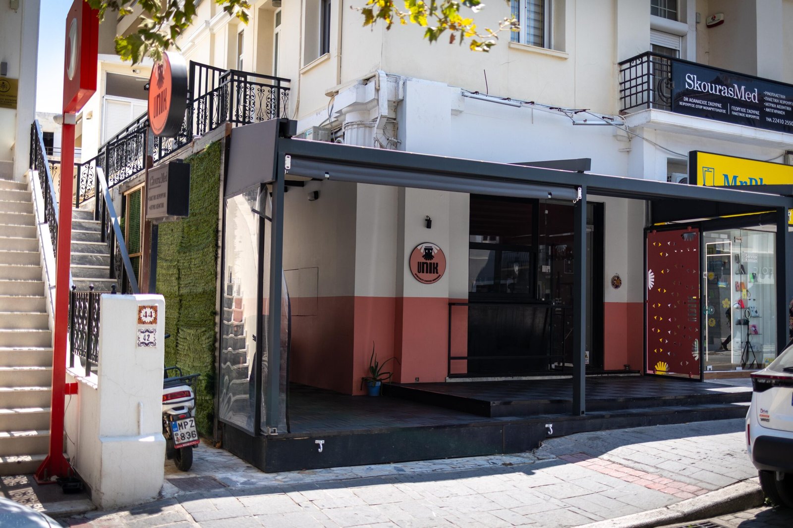 Exterior of Unik Specialty Coffee Brewers on a street corner in Rhodes Town, with the pink and dark shopfront