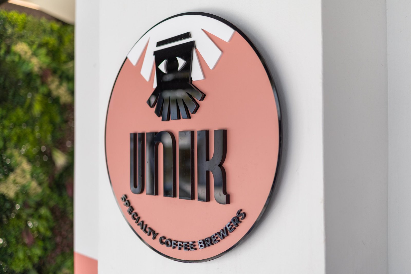 Close-up of the Unik Specialty Coffee Brewers squid logo on a salmon pink sign