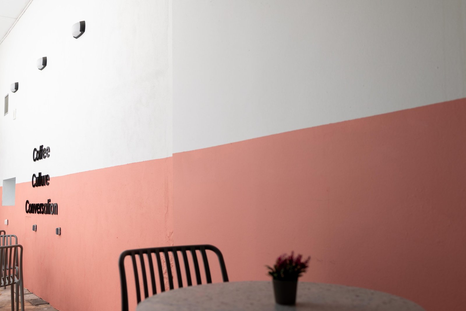 Coffee, Culture, Conversation lettering on the pink and white wall at Unik Specialty Coffee Brewers