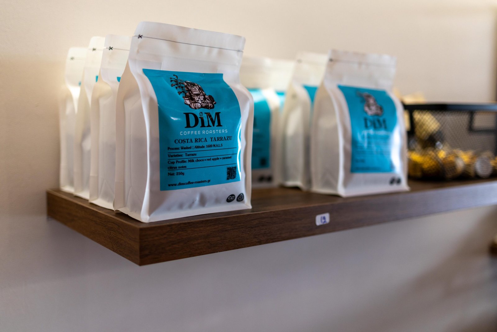 Bags of DiM Coffee Roasters beans, including a Costa Rica Tarrazu single origin, on a shelf at Unik