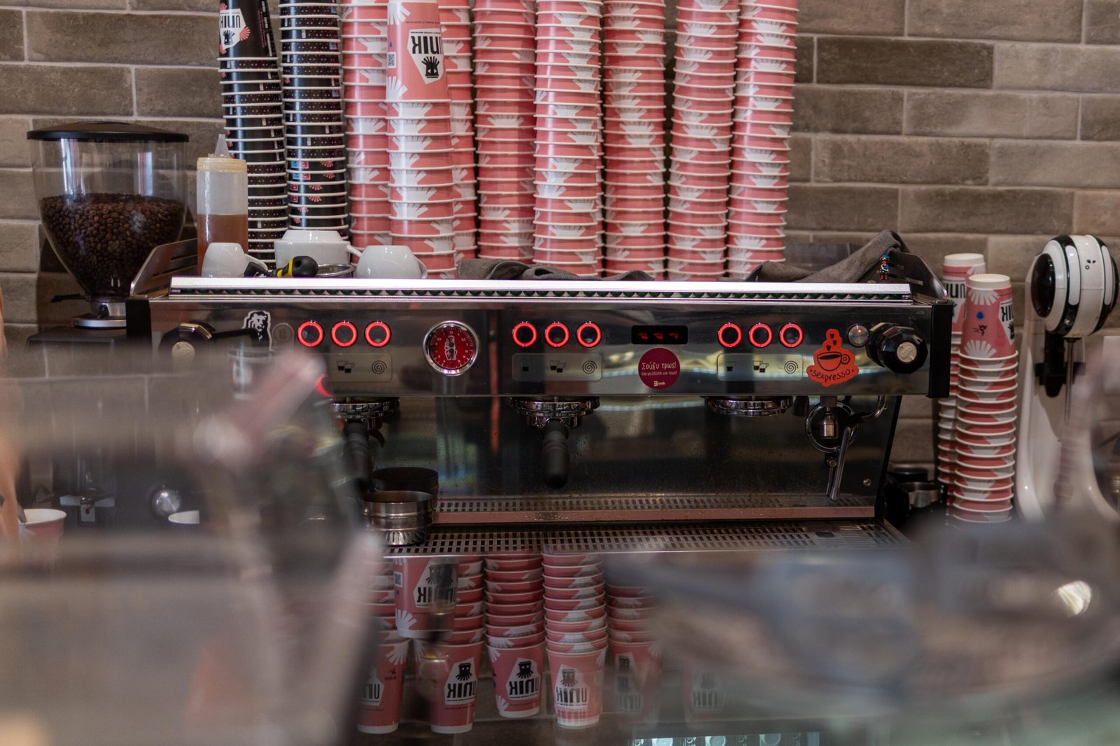 The espresso machine at Unik Specialty Coffee Brewers with branded cups stacked on either side