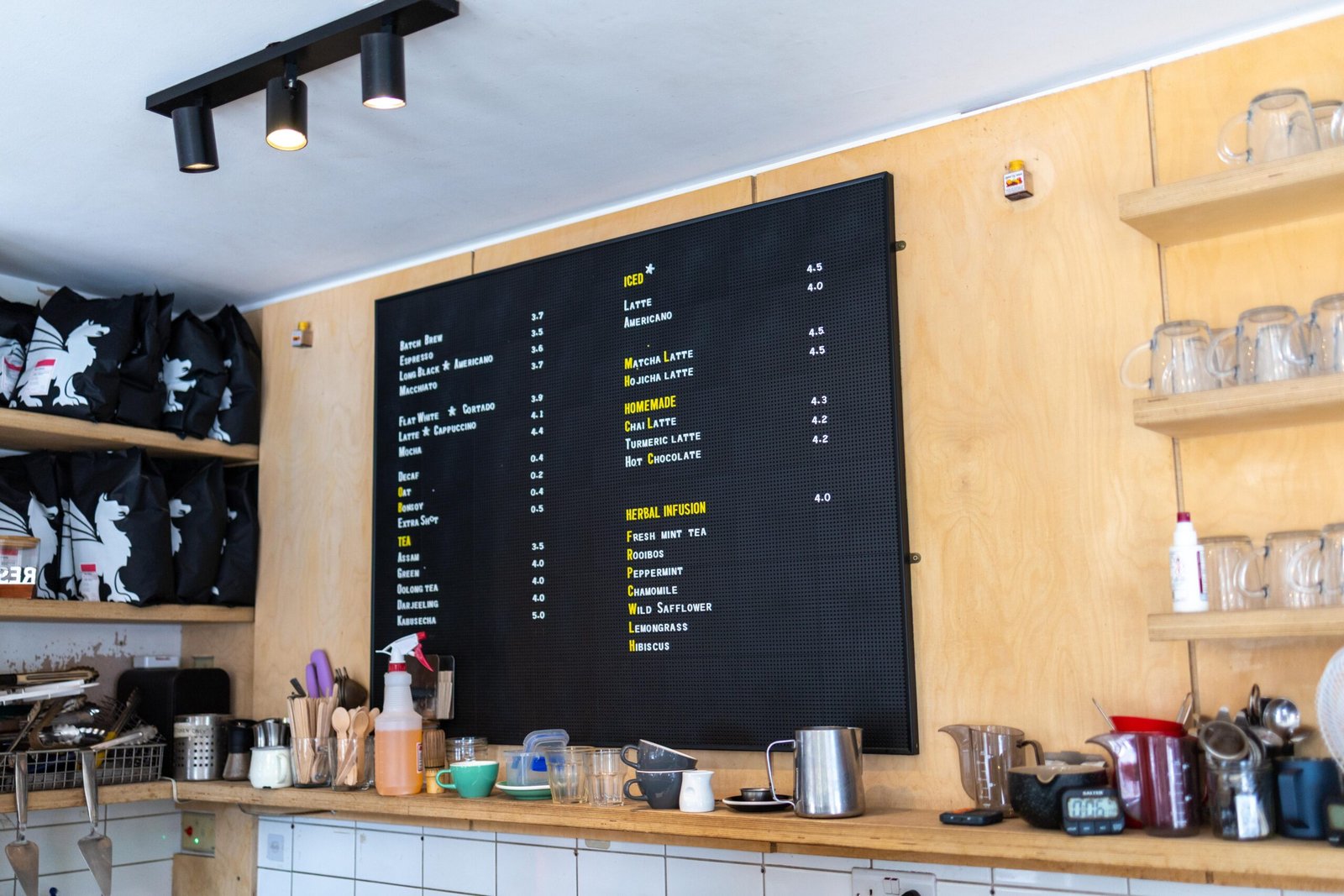 The full menu board at Velasquez and Van Wezel above plywood shelving, with retail coffee bags displayed alongside