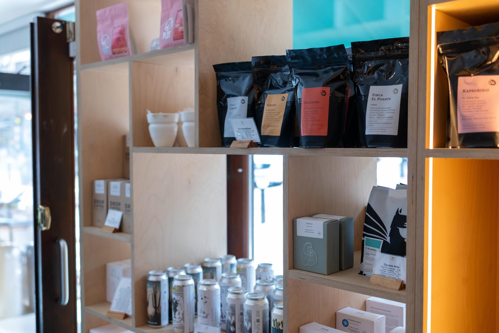 Retail shelf at Velasquez and Van Wezel showing Finca El Puente and Gachatha coffee bags alongside a Square Mile bag