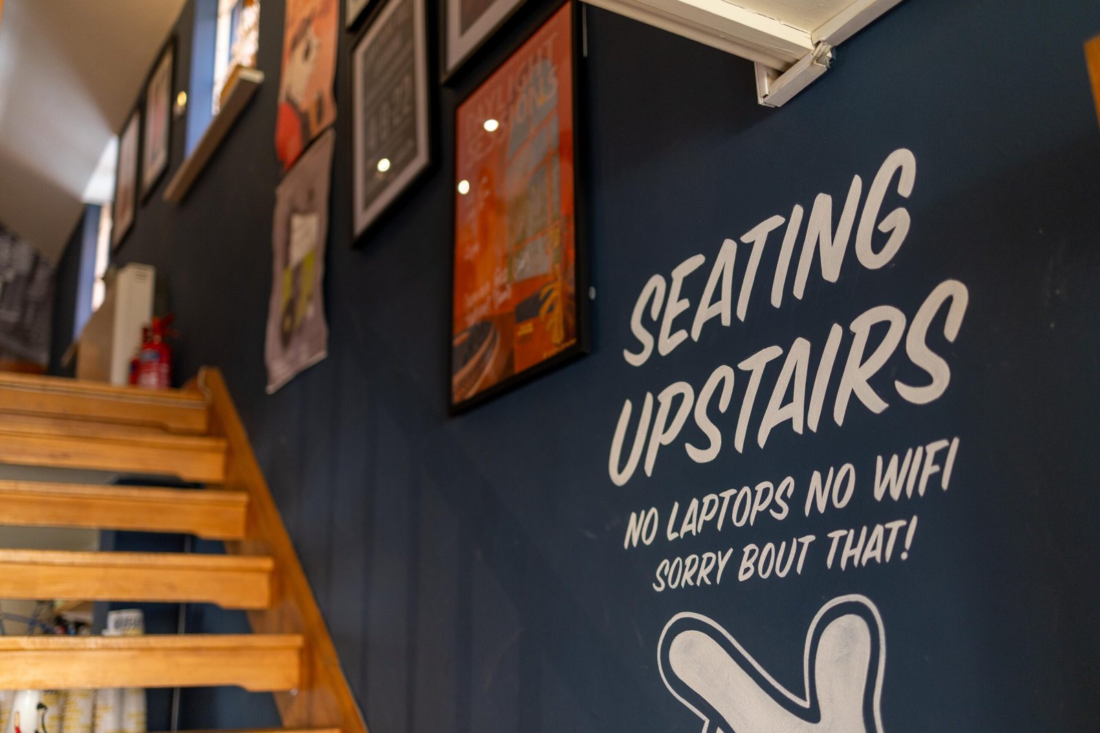 A handwritten sign reading Seating Upstairs, No Laptops No Wifi at Yellow Bourbon on Angel Street