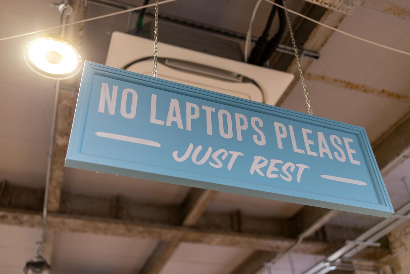 A blue sign reading No Laptops Please, Just Rest, hanging inside Yellow Bourbon's Weedon Depot