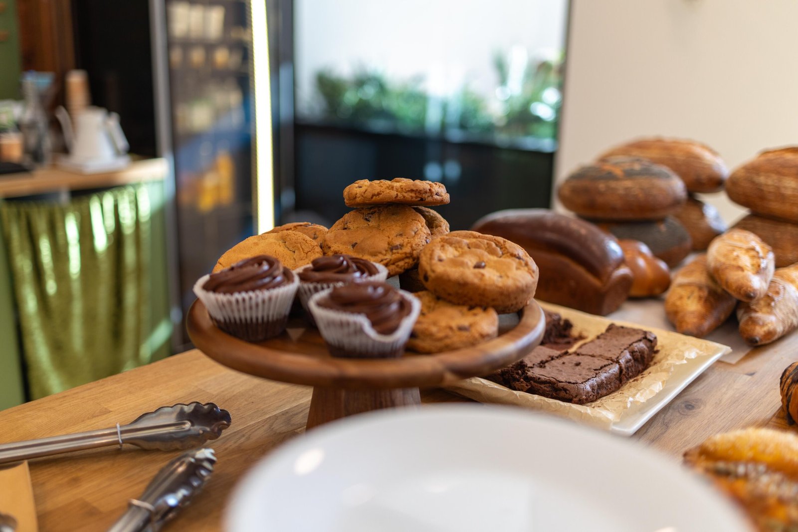 Stacked loaves, cupcakes, cookies and brownies on display on wooden boards