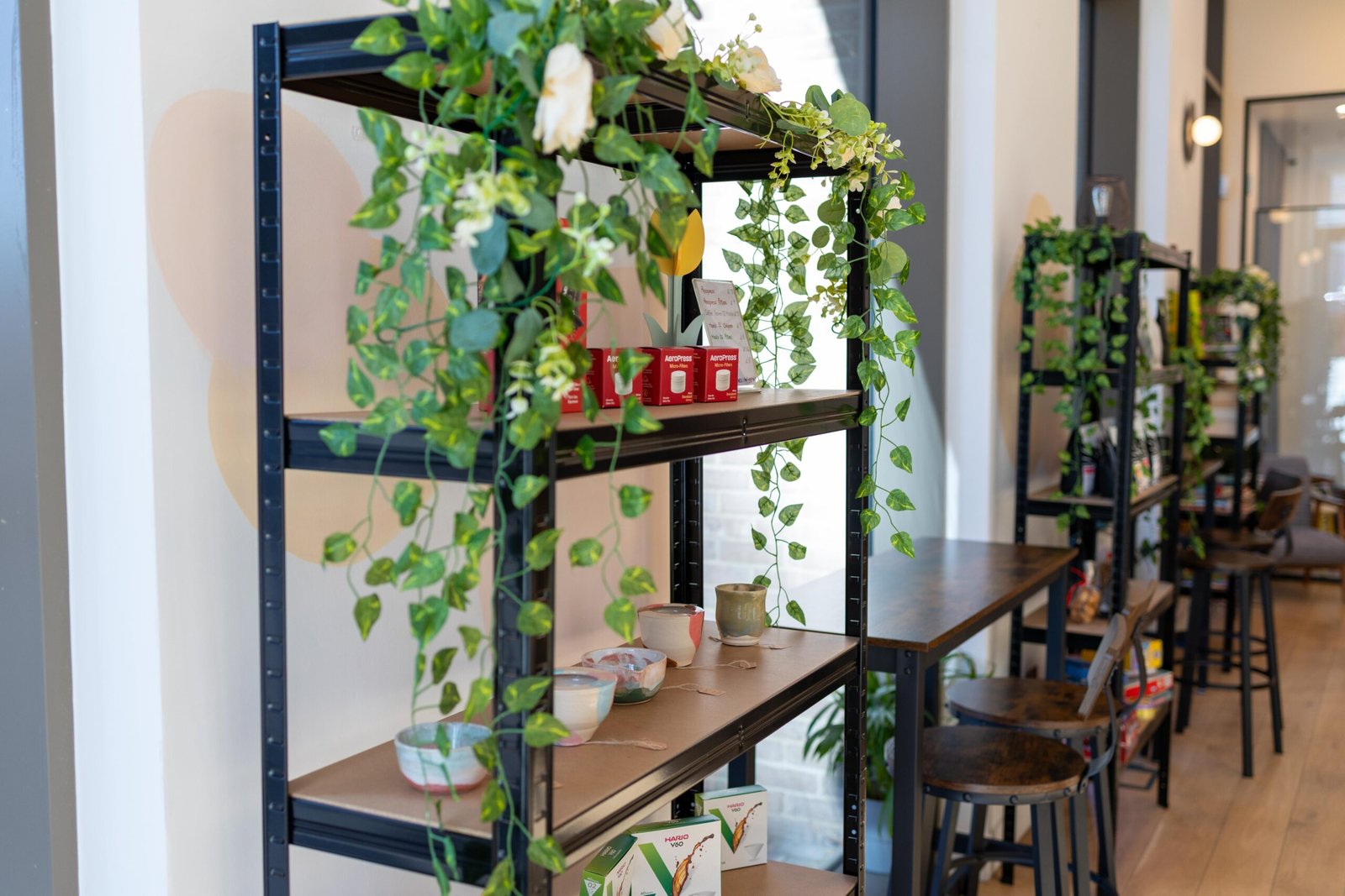 Shelving dressed with trailing vines and white flowers, with ceramics on display at Holy Grain & Brew