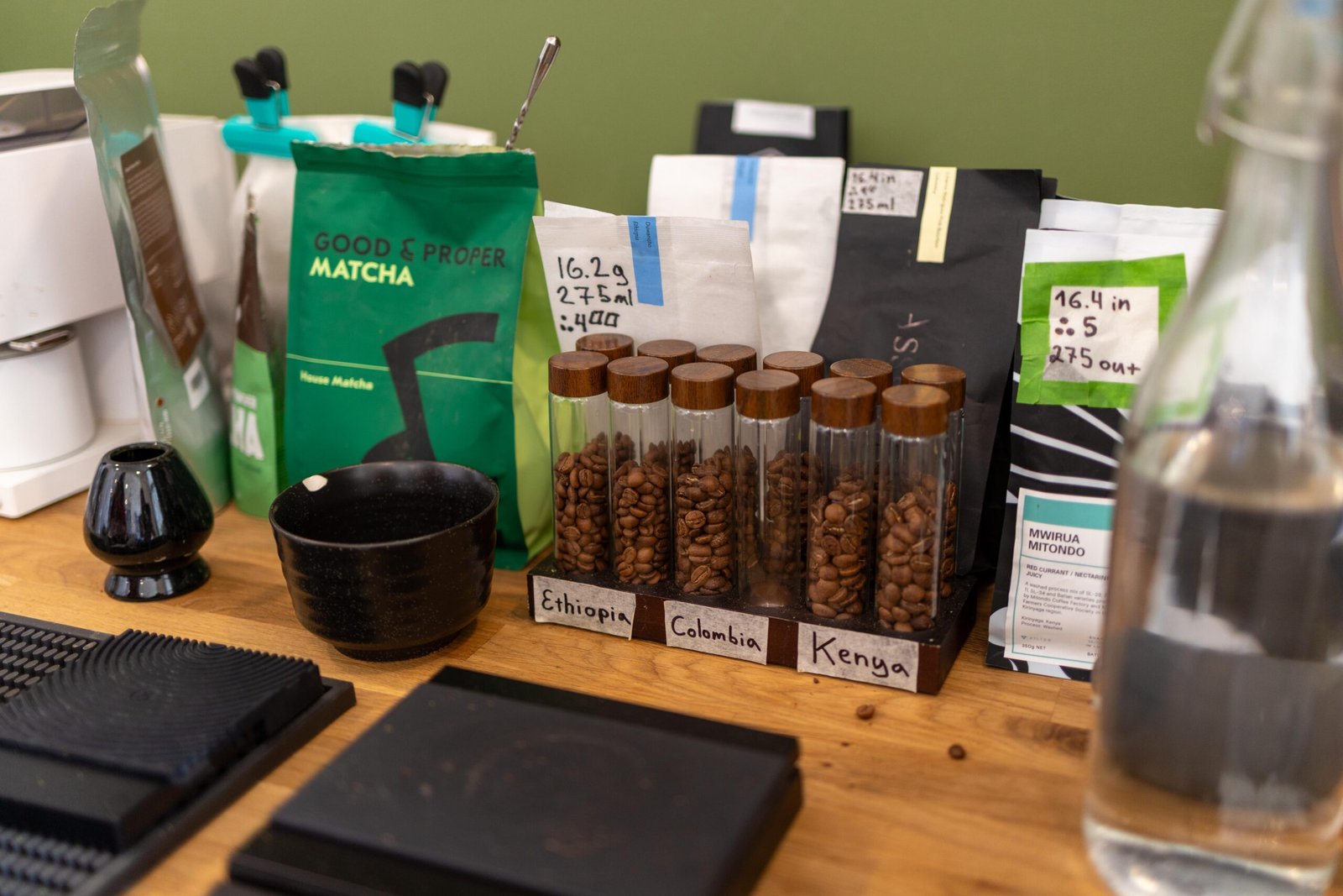 Single-origin coffee bean samples labelled Ethiopia, Colombia and Kenya, with a bag of Good & Proper Matcha behind