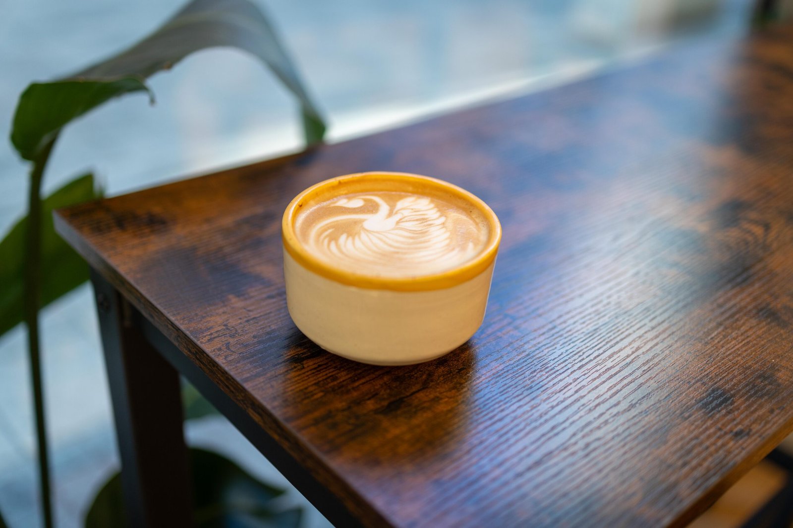 A latte with swan latte art on a wooden table