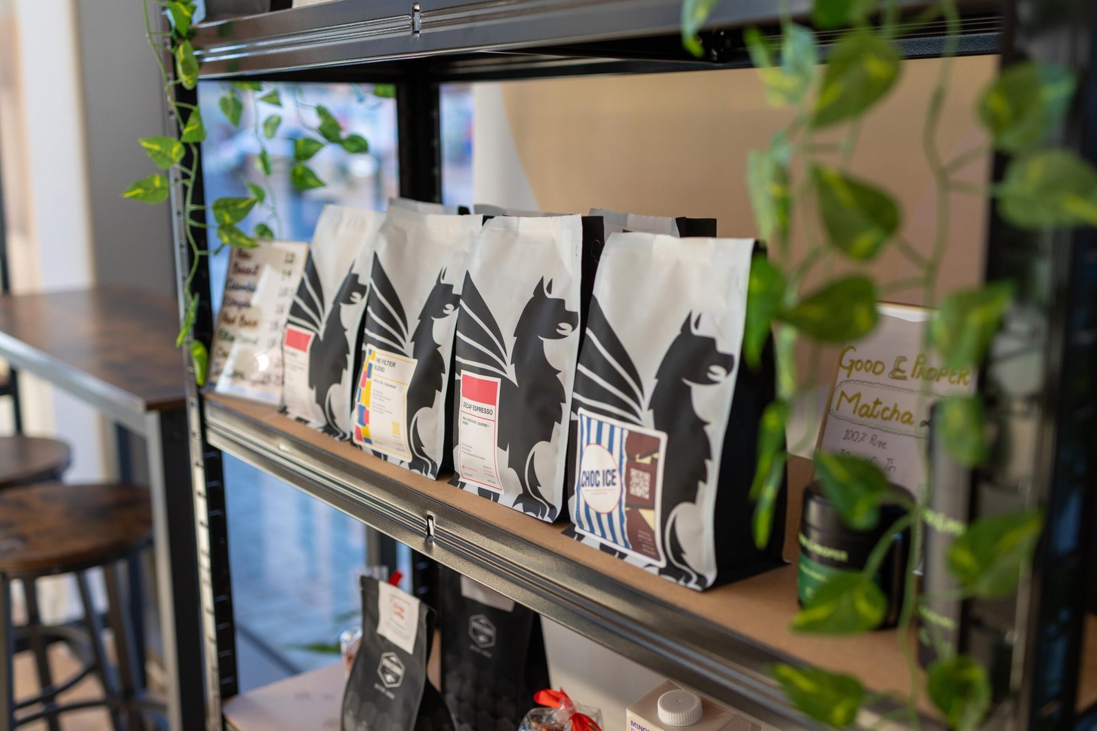 Retail coffee bags and a Good & Proper Matcha sign on a shelf at Holy Grain & Brew