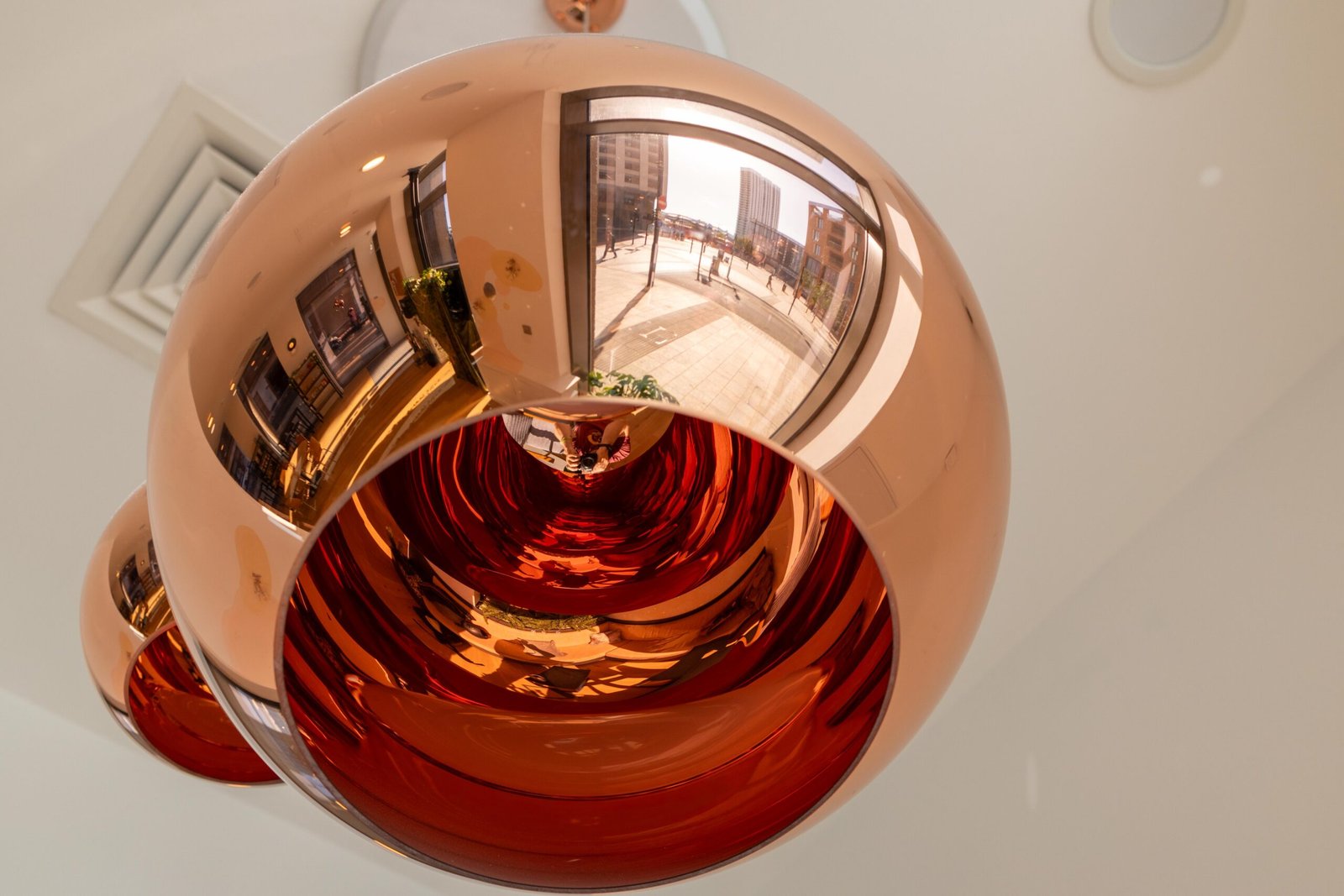A copper pendant light fixture reflecting the street outside