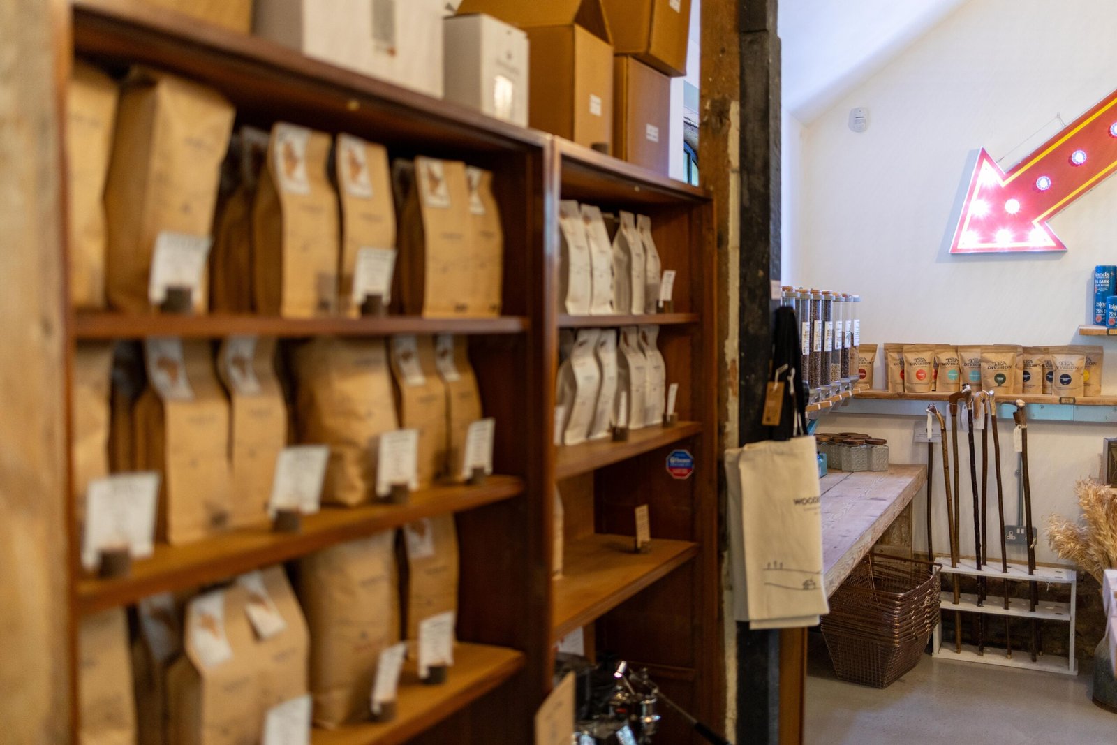 Retail shelves of coffee bags at Wooden Hill Haynes, with a lit up arrow sign on the wall