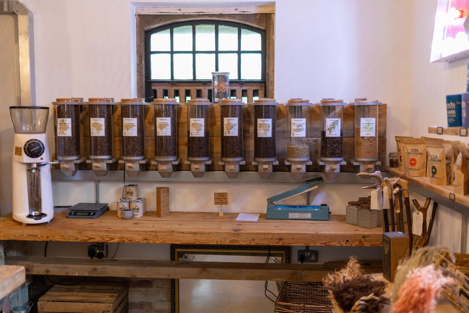 A row of bulk coffee refill dispensers and a heat sealer at Wooden Hill Haynes