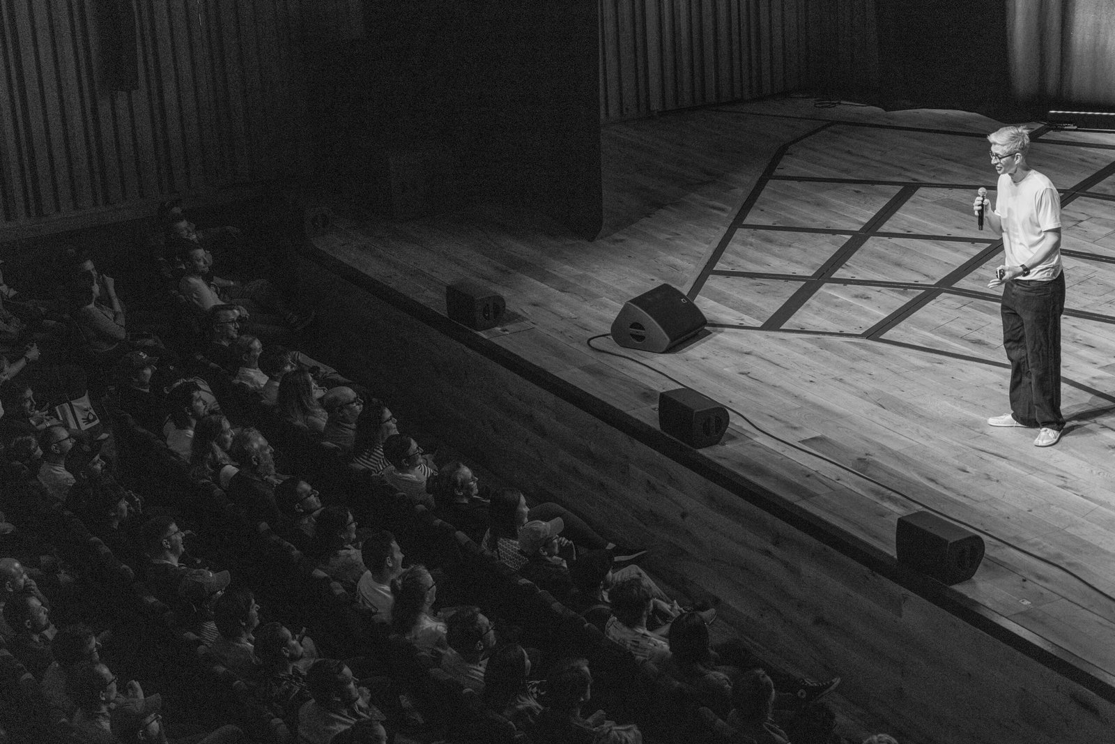 Black and white wide shot of James Hoffmann on stage with the audience in Beacon Hall