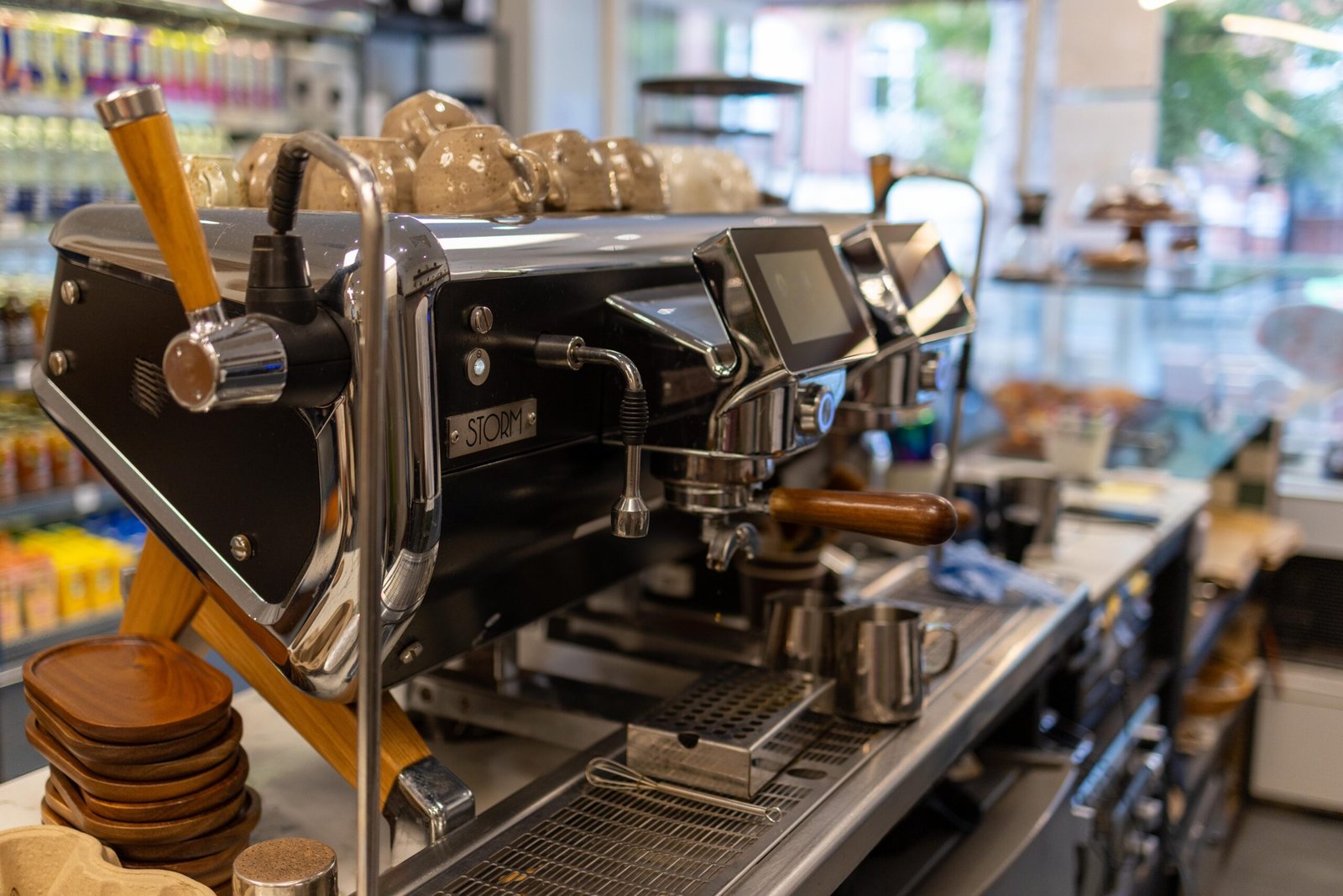 The espresso machine behind the counter, with wooden coasters and stacked cups