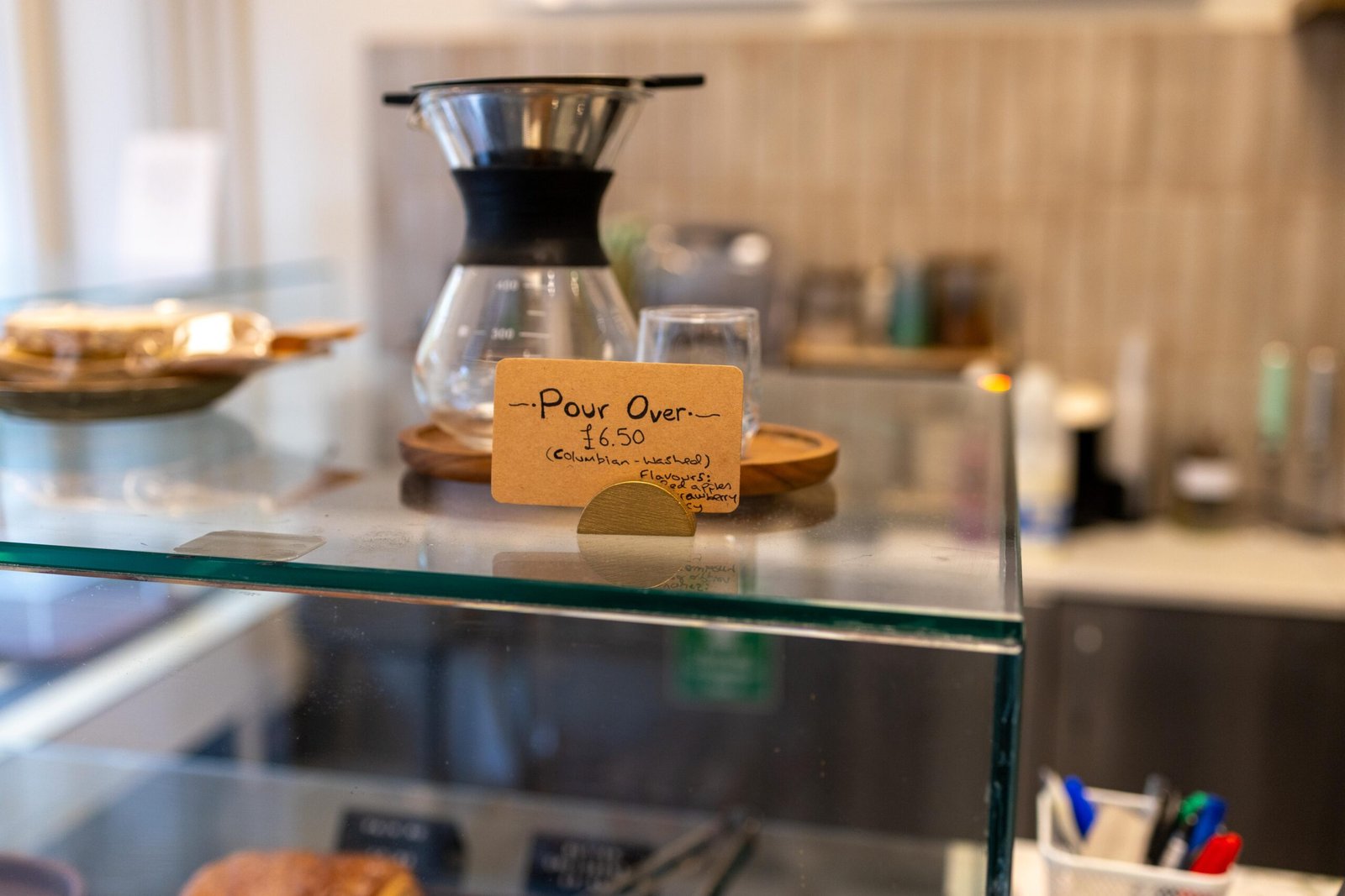 A pour-over V60 setup with a handwritten sign listing the Colombian washed filter coffee