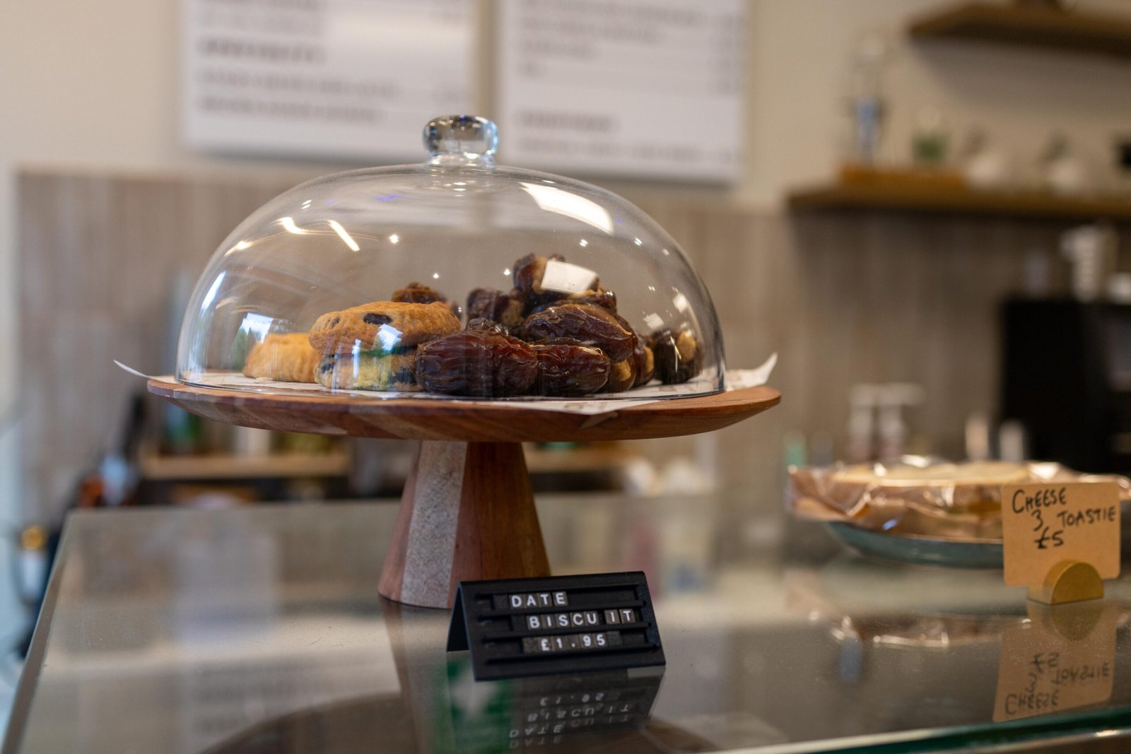Date biscuits displayed under a glass dome on the counter, priced at £1.95