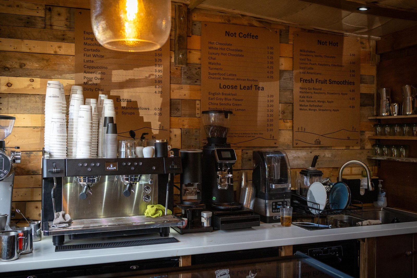 The full espresso bar and menu board at Wooden Hill's Maulden cafe, with retail shelving