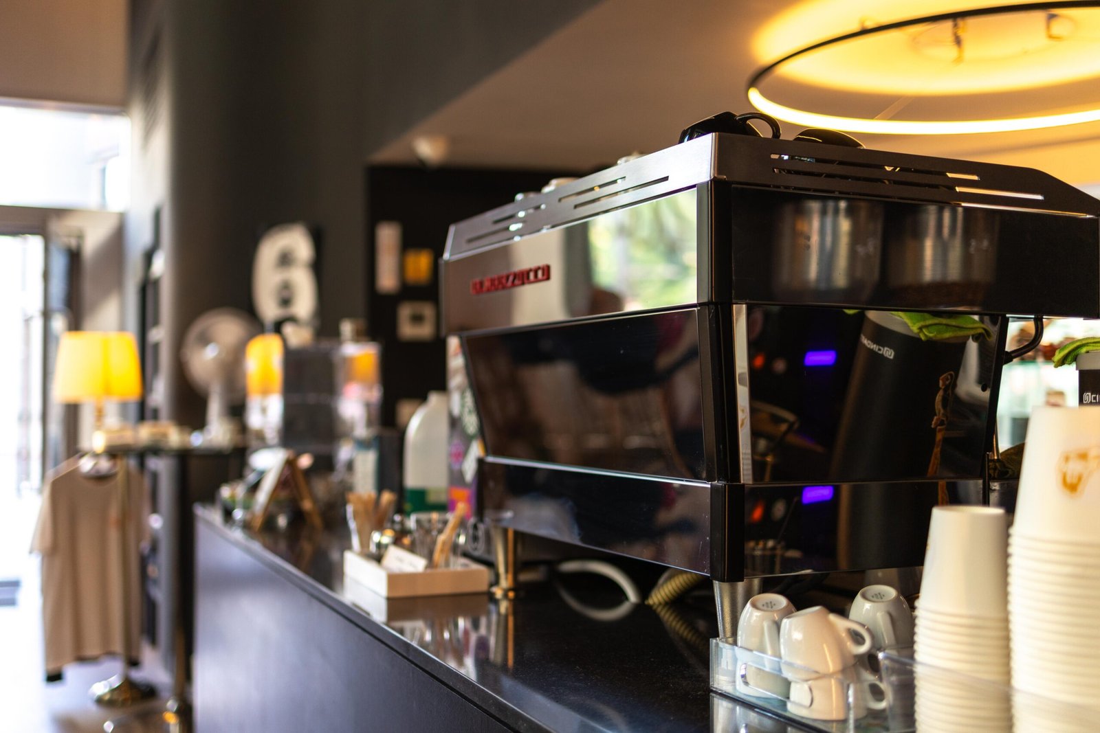 Espresso machine and stacked cups on the counter, with a numeral six marking the shop's sixth anniversary visible behind