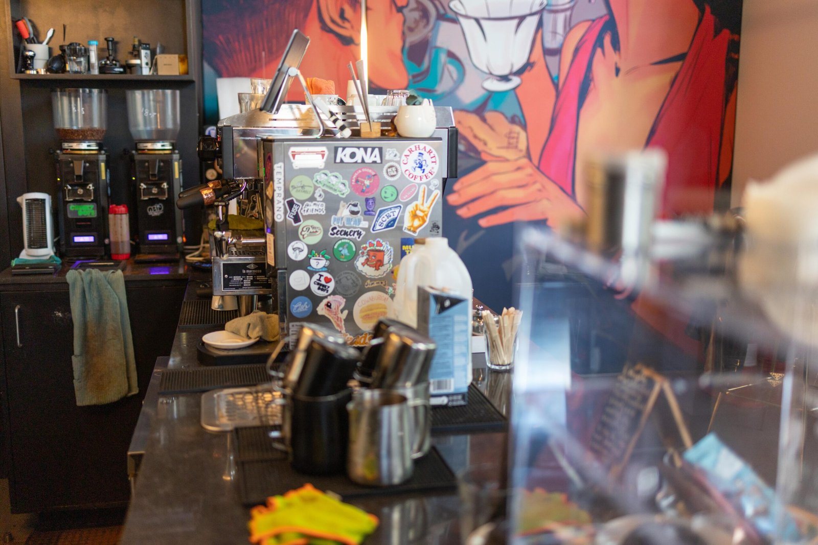 The counter with a stickered grinder, including a Scenery sticker, and the mural visible behind