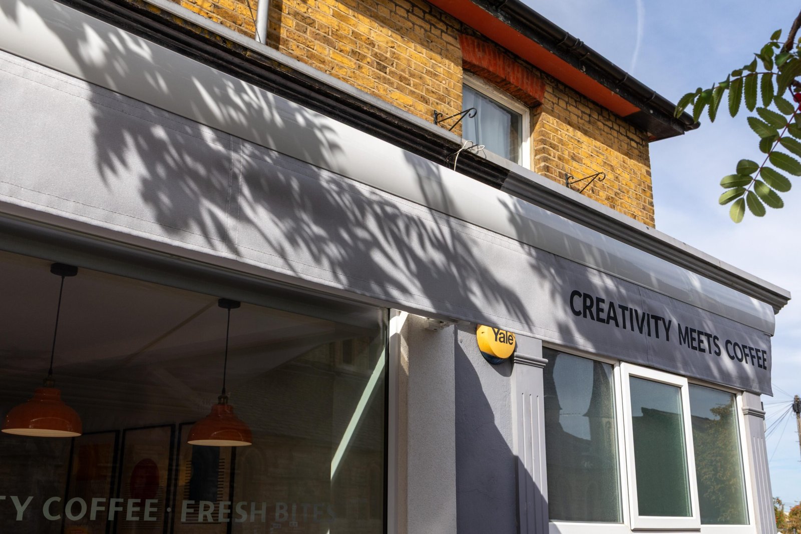 The grey-painted frontage and awning of Simba Bru beneath the yellow-brick upper storey