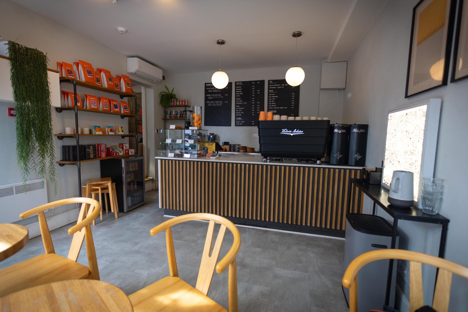 The compact interior with three tables and a long bench along the window