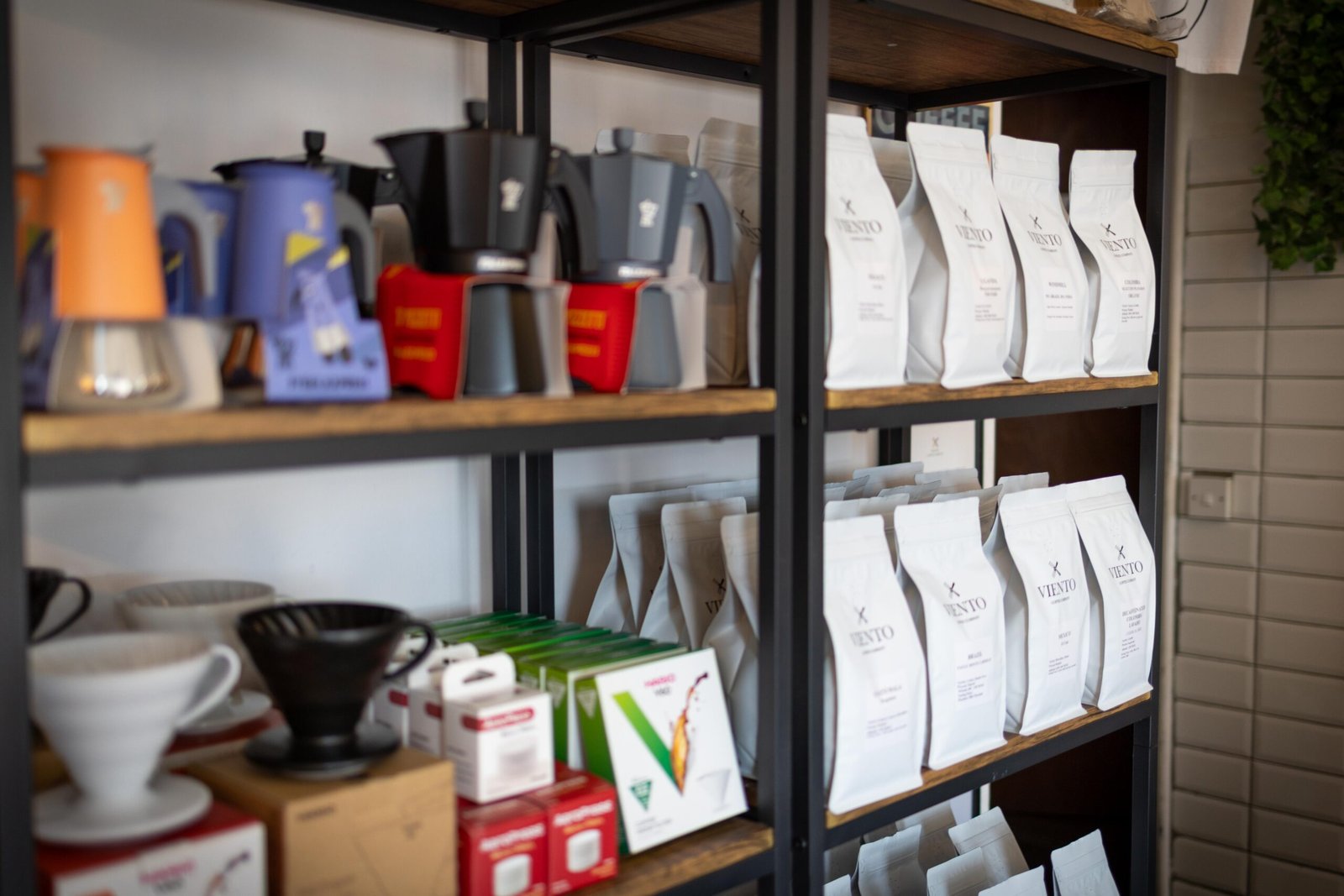 Exposed metal shelving displaying bags of coffee beans and brewing equipment