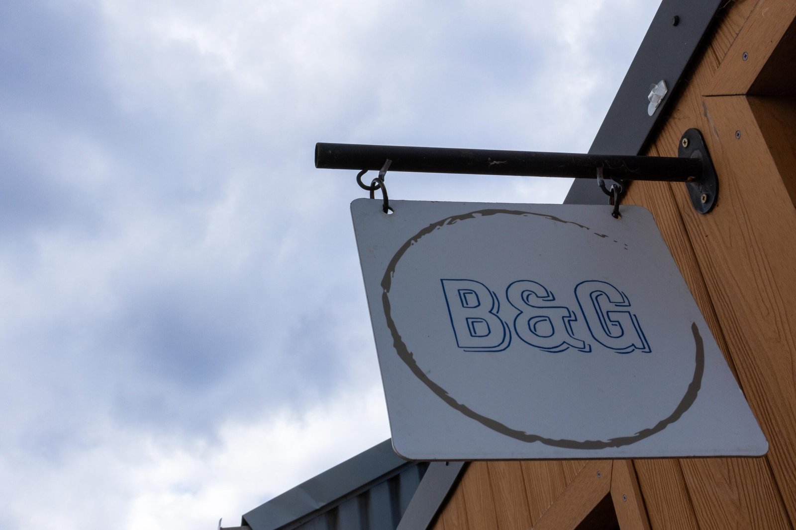 Bean & Gone Coffee sign hanging from the wooden kiosk against a cloudy sky