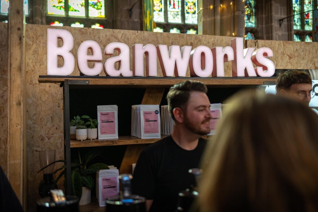 Beanworks sign above the stand, with a team member behind the counter and stained glass windows behind