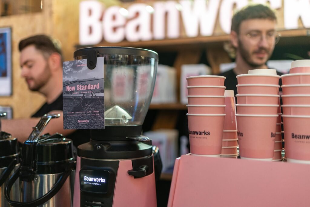 Beanworks team members behind a pink grinder and stacks of pink Beanworks cups