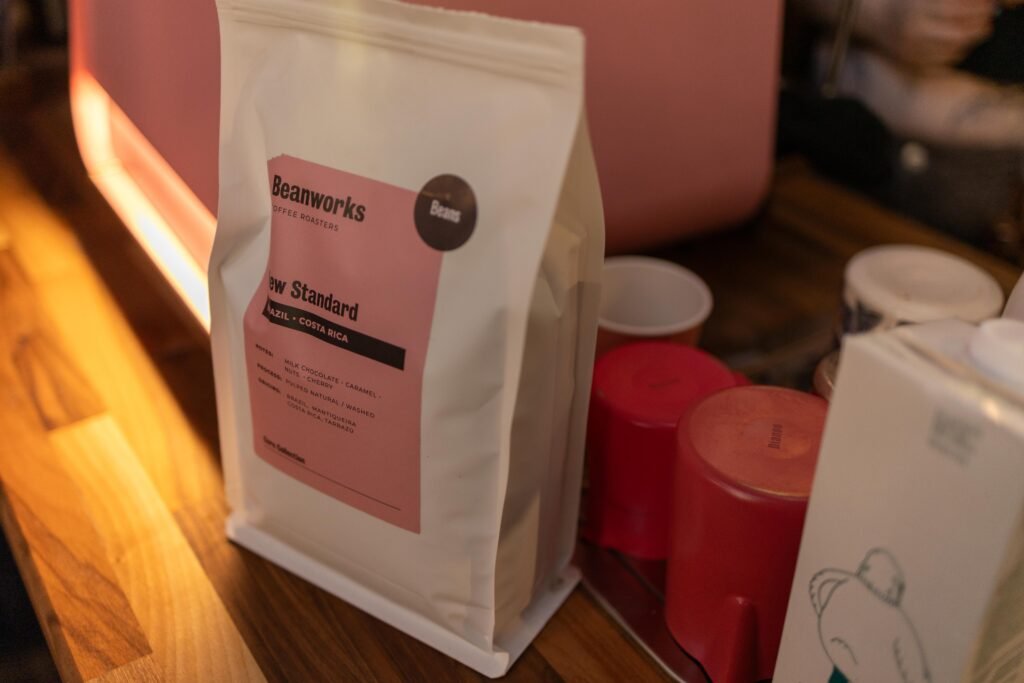 Beanworks coffee bag with a pink label on a wooden counter next to tasting cups