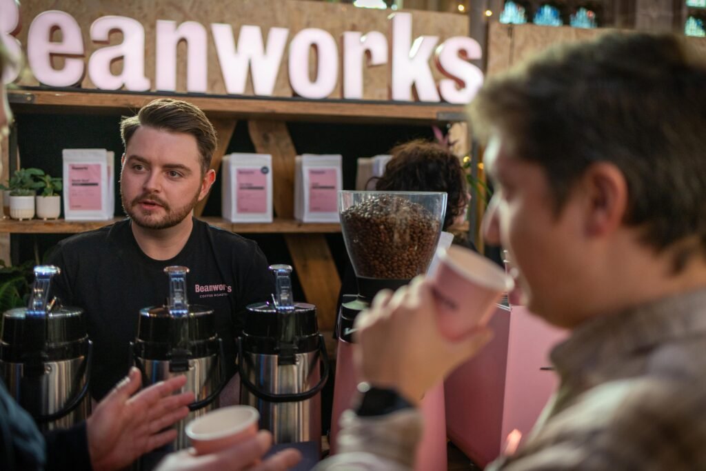 Beanworks team member talking with a visitor sipping a coffee at the stand