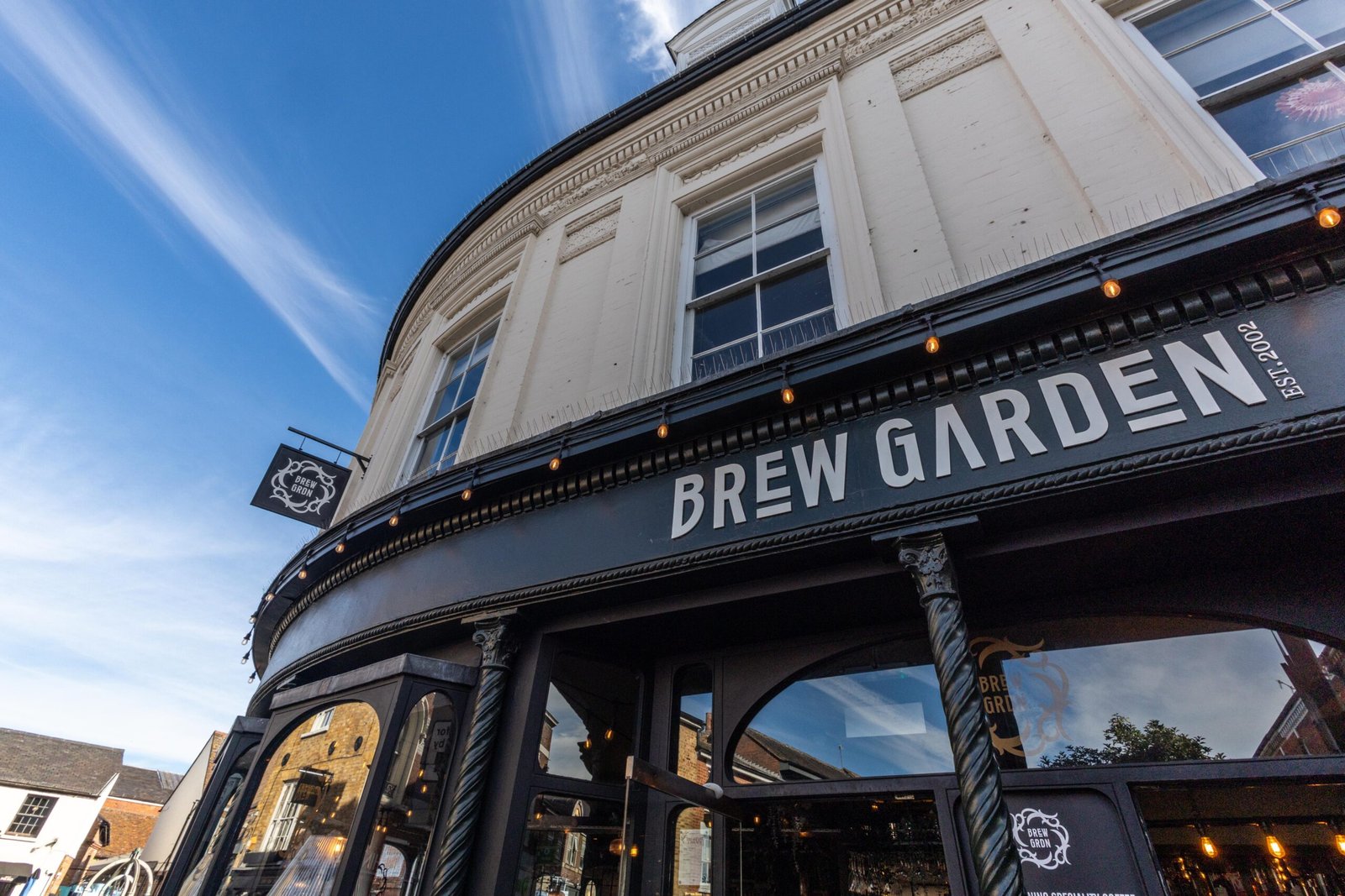 Brew Garden dark-painted exterior and sign against a blue sky