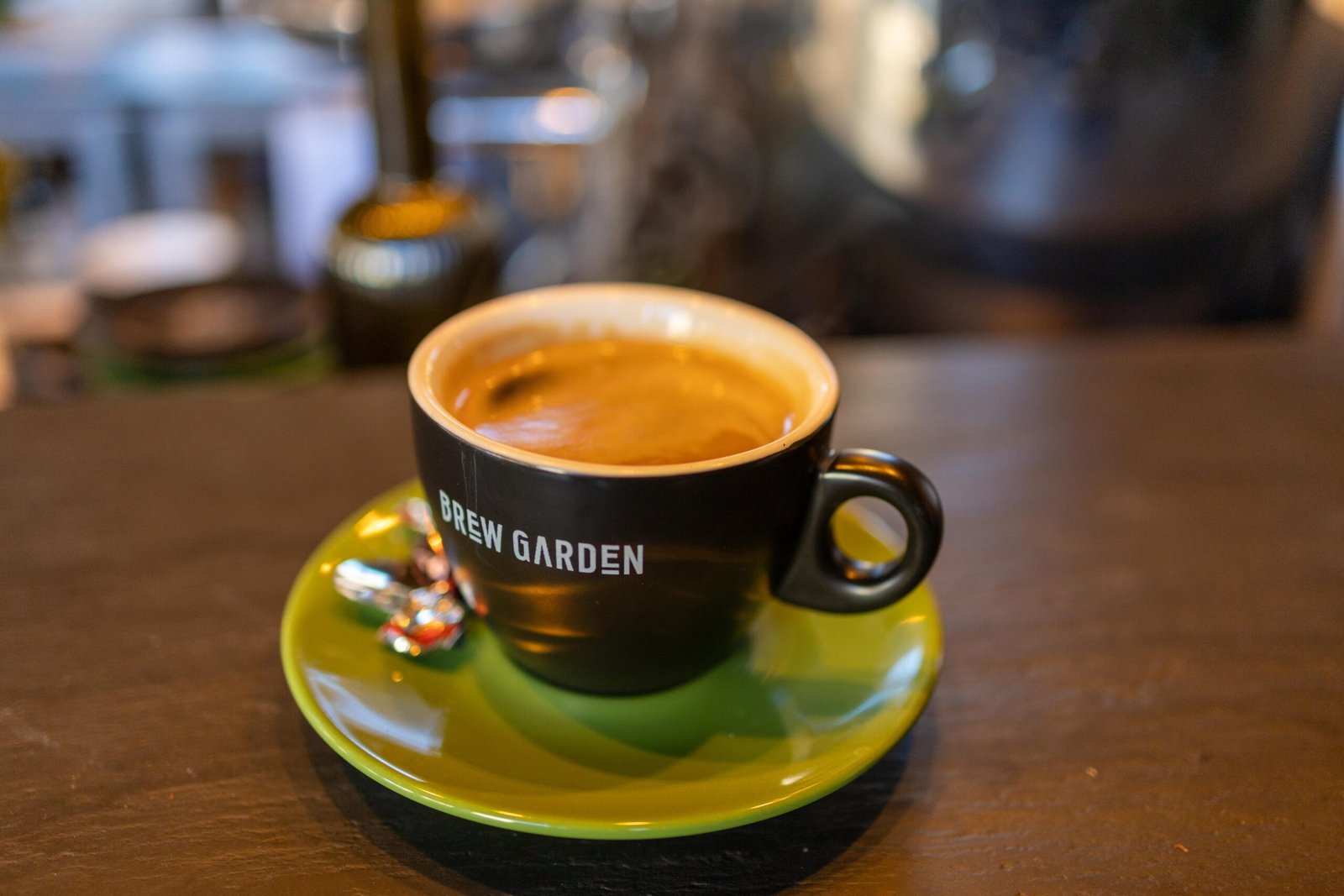 Espresso in a black Brew Garden cup on a green saucer