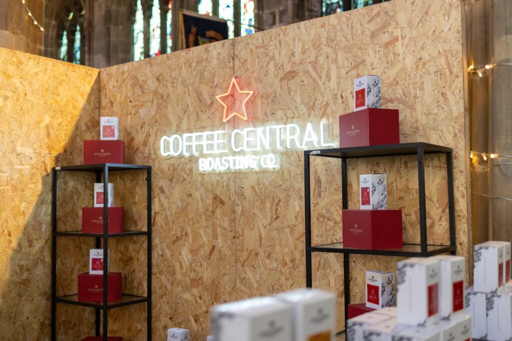 The Coffee Central Roasting Co neon sign above shelves of red boxes and coffee packs