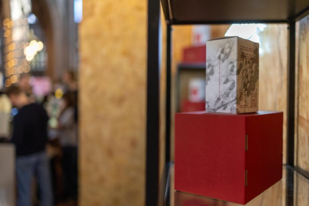 A single Coffee Central coffee box on a red display cube, with festival visitors blurred behind