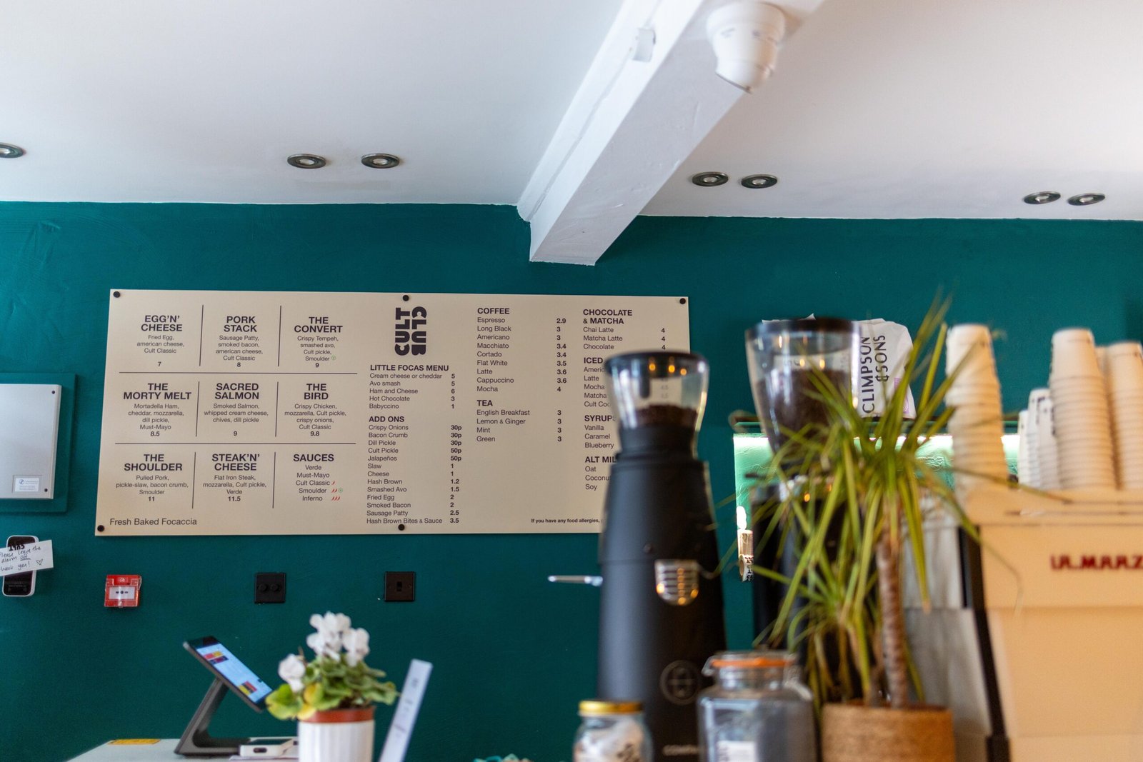 Menu board on the teal wall at Cult Club Coffee, one of the newest coffee shops in Hertford
