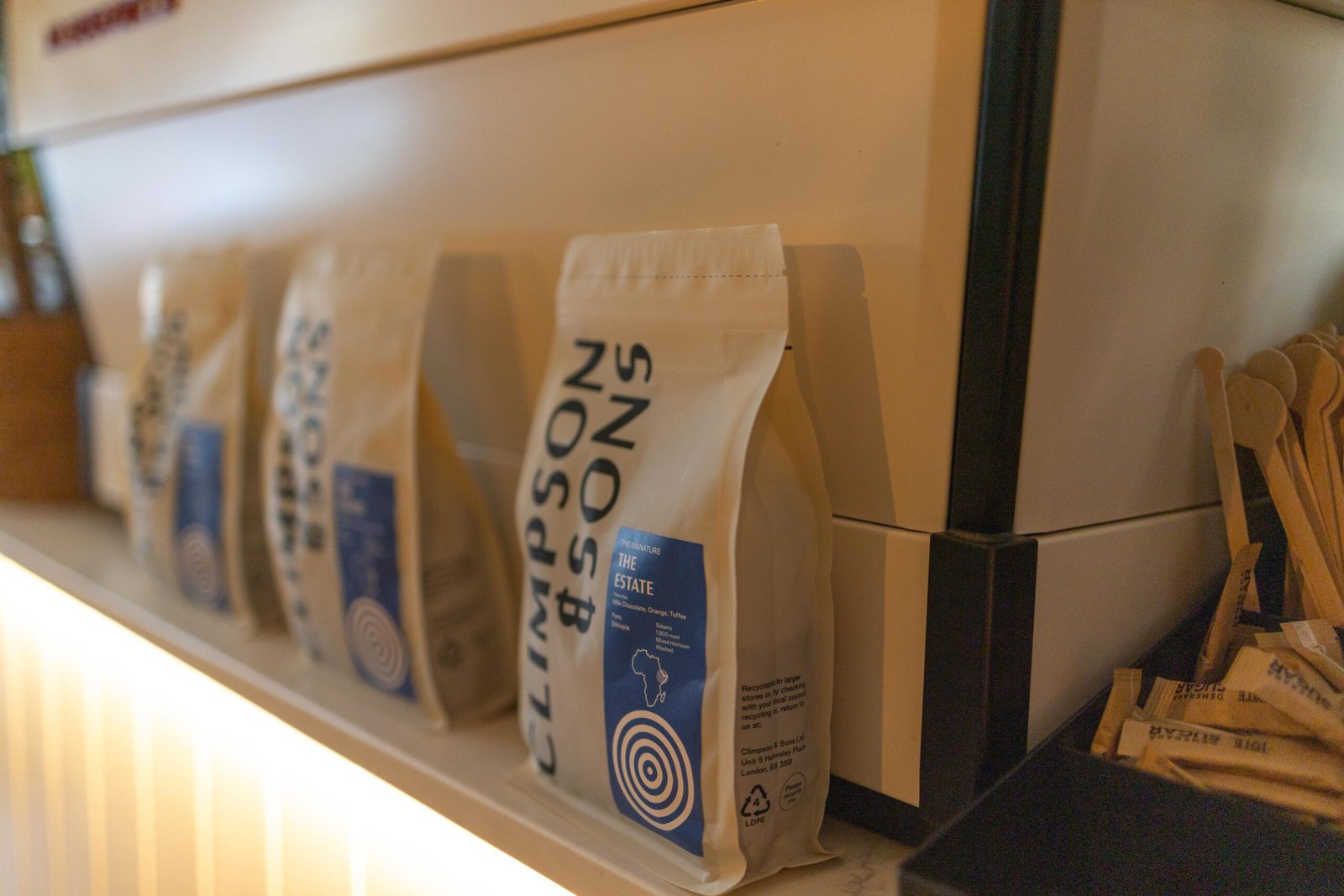Bags of coffee on an illuminated shelf at Cult Club Coffee