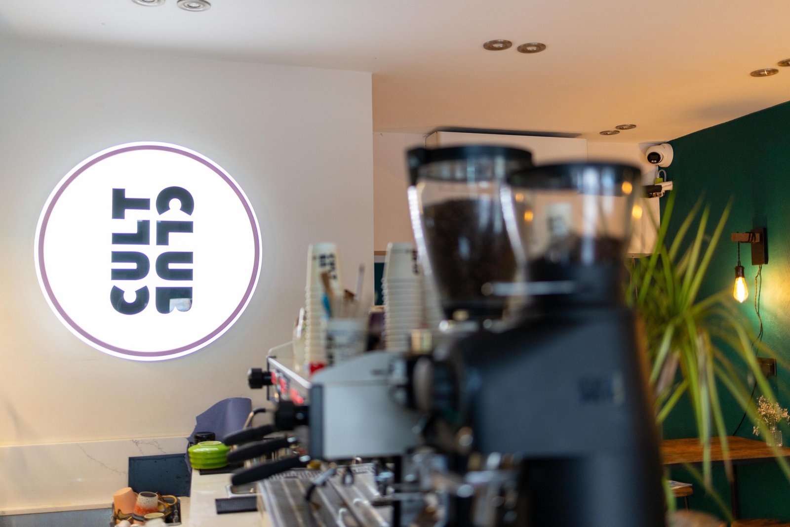 Grinders and espresso machine beneath the Cult Club logo